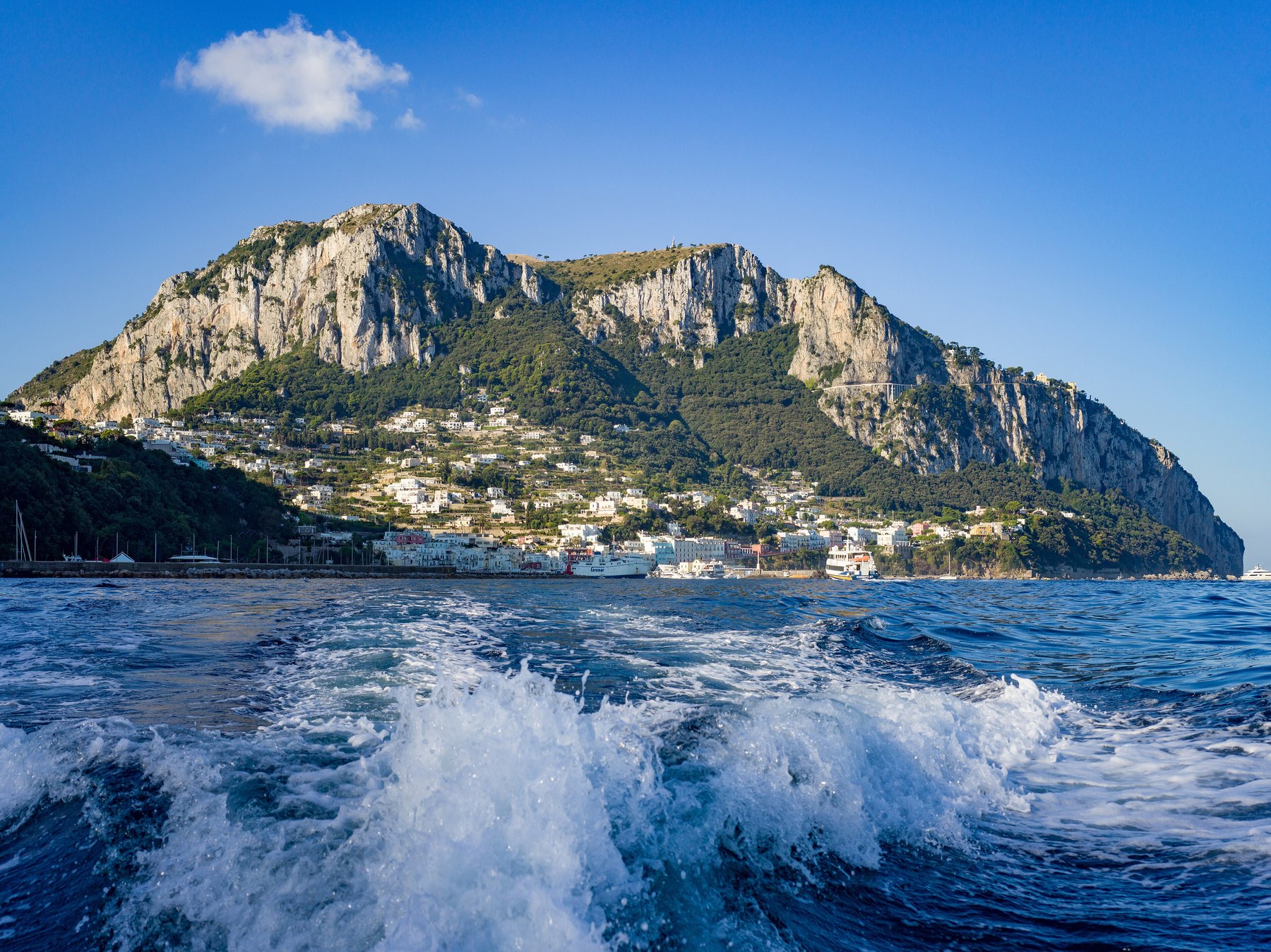 The island of Capri seen from the sea, with the wake of a boat in the foreground