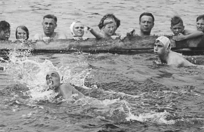 Two swimmers at the finish line, among the crowd, in a black and white photograph