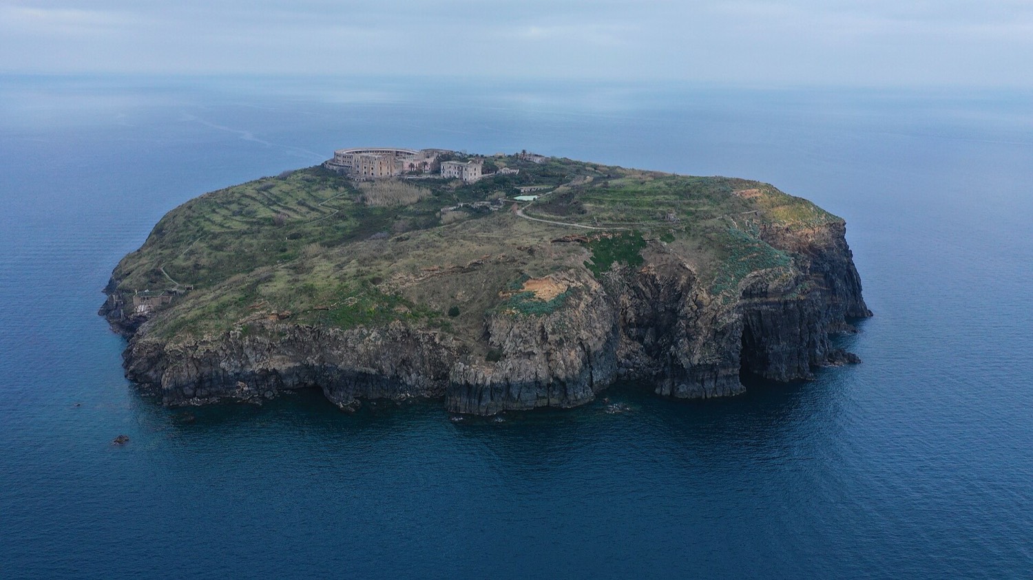Aerial view of the island of Santo Stefano: the circular prison in the center of a green rock surrounded by open sea